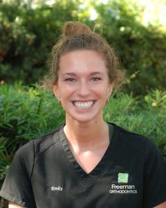 Smiling person in black shirt outdoors.