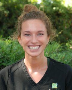 Smiling person in black uniform outdoors.